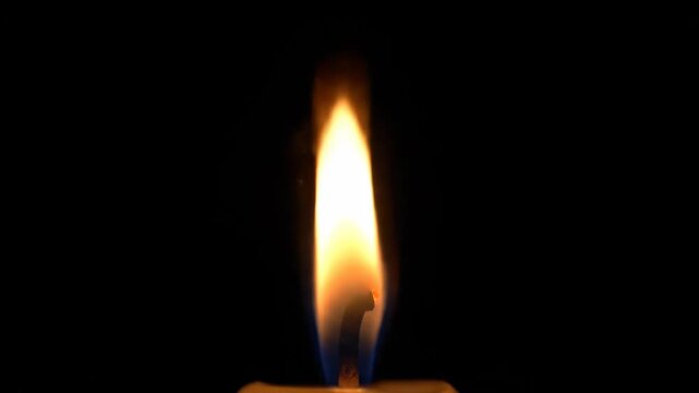 Candle Flame Burning Brightly in Dark Background with Warm Glow