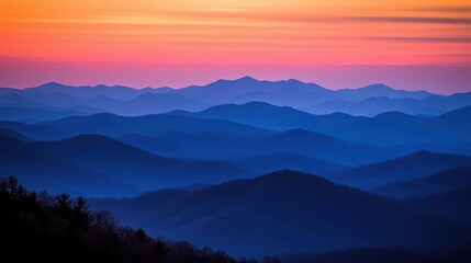 Obraz premium Majestic mountain ranges bathed in the soft glow of a colorful sunrise with layered peaks against a vibrant sky