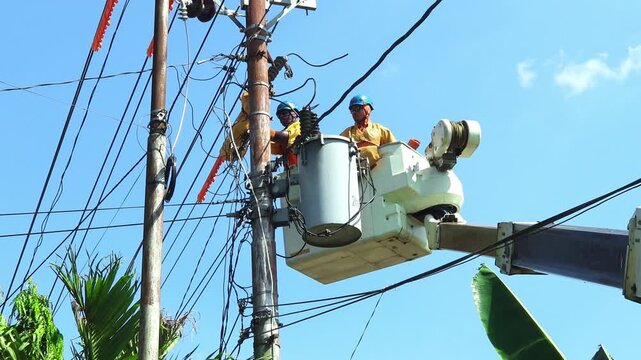 Power Line Technicians Inspecting Insulators and Cable Connections on a Single Phase Distribution Transformer
