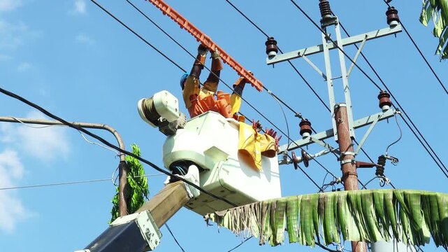 Electric Linemen in Full PPE Performing Live Line Maintenance Using Insulating Covers on Overhead Power Distribution Line