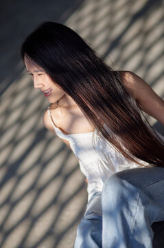 Young Woman with Long Hair in Natural Light and Shadow Patterns