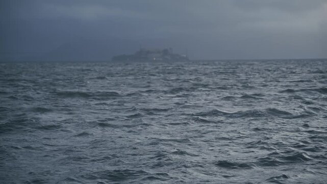 Hazy View Of Alcatraz Island Across Bay With Rough Swell, Dark Overcast Sky