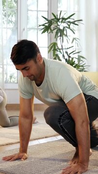 Indian Asian young couple joyfully practicing yoga together in their lavish home, executing Ek Pad Prasarita Padasana, or One-Legged Wide-Legged Forward Bend pose