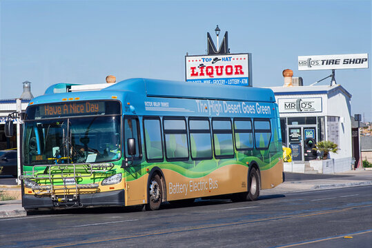 Electric bus paused on a commercial street in Barstow, illustrating public transportation in a Mojave Desert community. California, July 7, 2023.