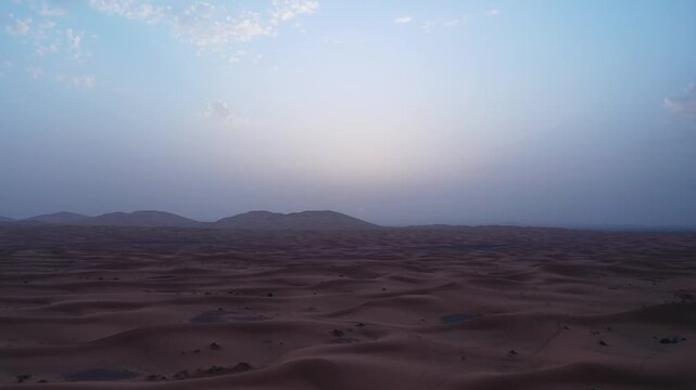 Drone aerial view of twilight over the Erg Chebbi sand dunes in Merzouga, revealing the peaceful atmosphere and endless beauty of Morocco's iconic Sahara Desert.