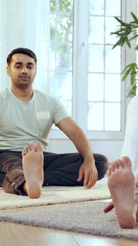 Indian Asian young couple learning yoga in the comfort of their lavish home, performing janu shirasana or head to knee pose together, enhancing flexibility and mindfulness in a serene environment