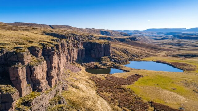 Expansive Aerial View of Dramatic Mountain Range Cliffs and Hidden Lakes Under Bright Daylight
