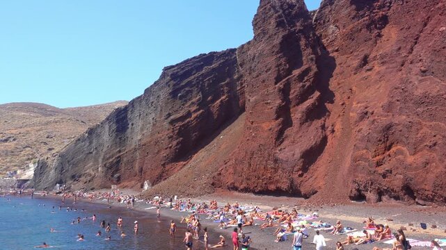 People relaxing on famous Red Beach in Santorini, Greece