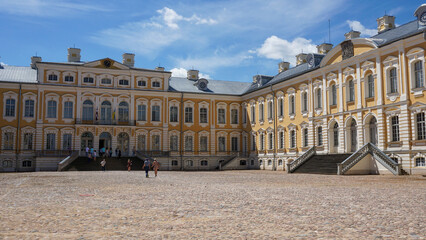 Obraz premium Rundale Palace with Baroque architecture featuring ornate columns, sculptural gate and wide cobblestone courtyard. Historic residence, European heritage, tourism destination and classical design