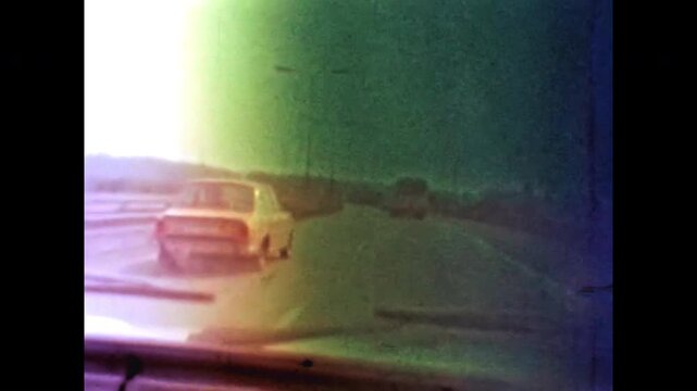 View through car windshield driving on multi lane highway. Vehicles move through automobile traffic. Road travel, transportation in motion. Pov drive in old film. Archival retro 1960s. Vintage archive