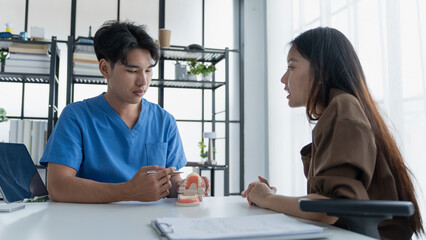 Fototapeta premium Dentist Examining Healthy Tooth Model While Consulting Patient