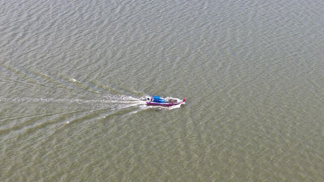 Aerial view of a fishing boat moving across coastal waters at Sungai Udang, leaving a wake.