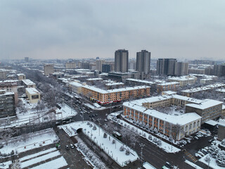 Obraz premium High angle aerial view of a wide urban intersection and surrounding streets, with a mix of Soviet-era and modern apartment blocks lightly covered in snow