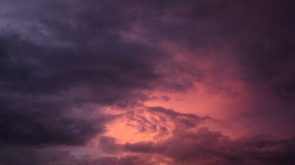 Obraz premium Dramatic sunset over a dark landscape with fiery clouds, atmospheric sky view, moody natural scenery, intense color contrast, evening atmosphere