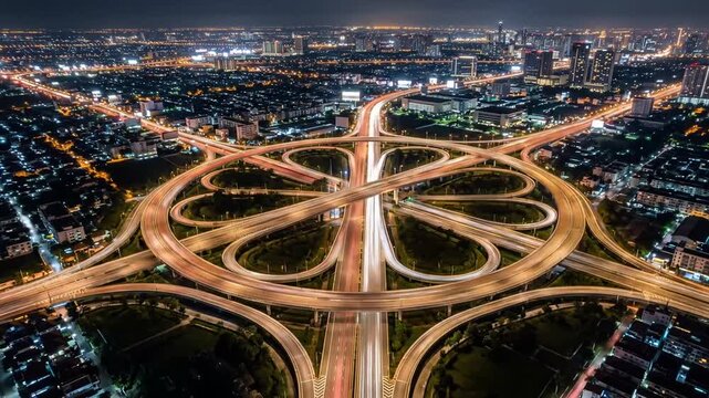Symmetrical aerial view of circular highway cloverleaf junction at night.