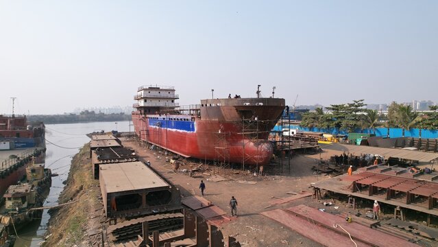Targhar, India - 23 December 2025: Aerial view of Maldar Shipyard with a large ship under construction, workers on site, metal structures, and industrial equipment.