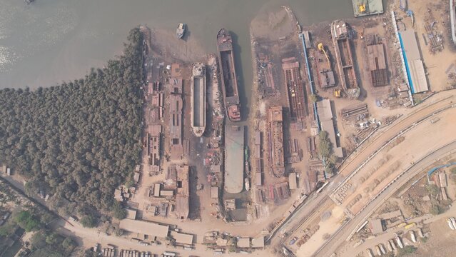 Targhar, Maharashtra, India - 23 December 2025: Aerial view of Maldar Shipyard with cargo ships and barges under maintenance, industrial structures, and dense mangroves along the waterfront.