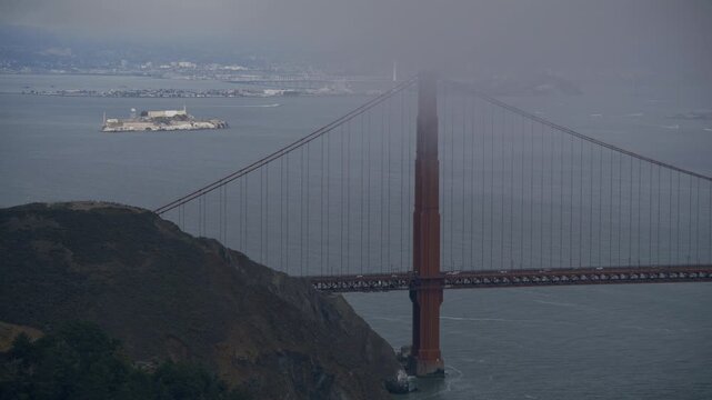 Golden Gate Bridge North Tower With View Of Alcatraz Island In San Francisco Bay With Overcast Sky