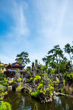 Ornate Chinese pavilion with dragon sculptures over garden pond at Sam Poh Tong cave temple, Ipoh, Malaysia