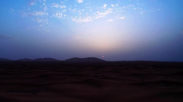 Drone aerial view of sunset over the Erg Chebbi sand dunes in Merzouga, capturing the tranquil atmosphere and timeless beauty of Morocco's iconic Sahara Desert.