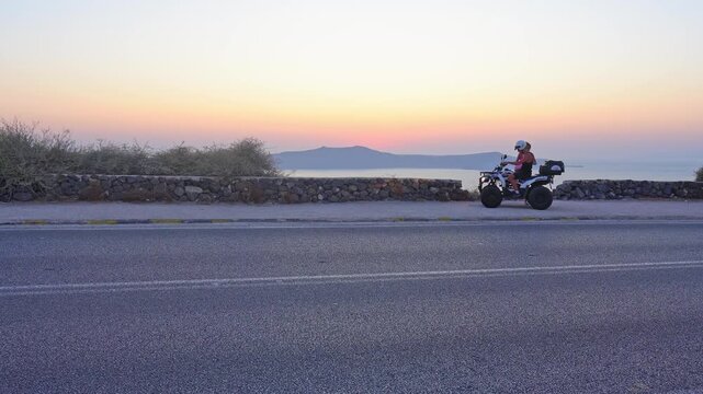 Couple riding a quad bike during a beautiful Santorini sunset