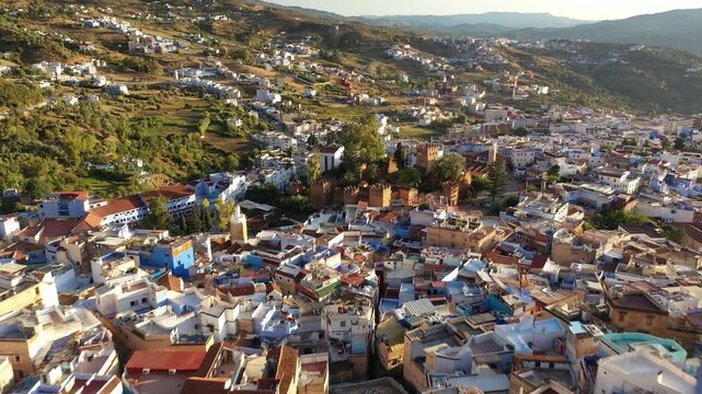 Drone aerial panorama of Chefchaouen, revealing its iconic blue neighborhoods cascading across the Rif Mountains, one of Morocco's most picturesque cultural and tourism destinations.