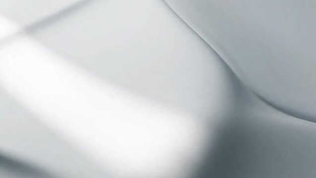 Abstract close-up of a smooth, flowing white and grey fabric surface with soft shadows and gentle curves, creating a minimalist and elegant texture.