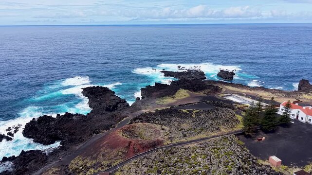 Drone aerial view of the rugged volcanic coastline on Sao Miguel Island Azores Portugal featuring black lava rock formations turquoise Atlantic waters dramatic ocean waves and breathtaking coastal sce