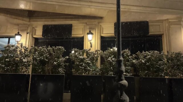 Tehran Iran sidewalk pedestrian and planter in urban street cafe teahouse at night snowfall in winter season luxury upscale vintage of illuminated facade moody decorative boutique downtown warm light