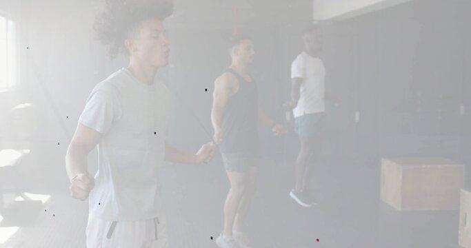 Vertical image: Left jumper starting skipping, three men syncing rhythm, skipping ropes in gym
