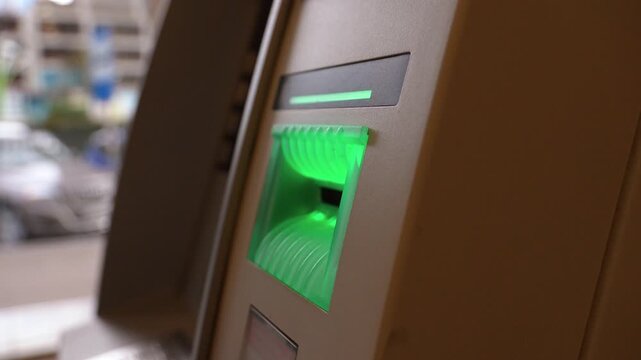 Close-up of a woman inserting a credit card into an ATM opening her bank account to conduct a financial transaction and withdraw money from a cash machine