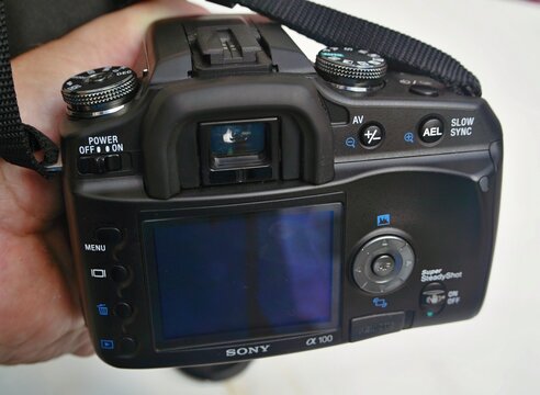 Person holding Sony Alpha A100 DSLR camera showing back view
