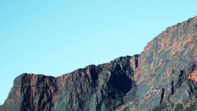Bright sky above a large mountain range with various colored rock layers. The scene shows clear weather and natural beauty in a remote location.