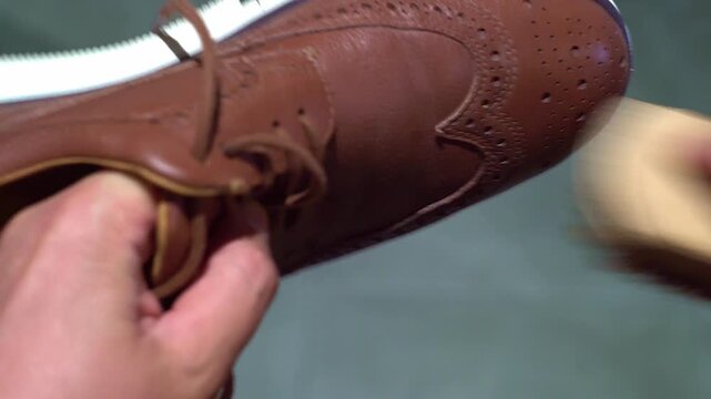 A man is brushing brown brogues