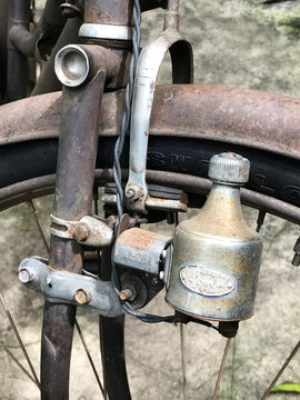 Close-up of a vintage bottle dynamo generator attached to the rusty front fork of an old classic bicycle.