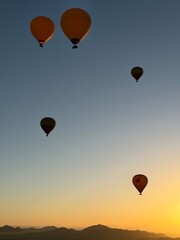 Fototapeta premium Hot air balloons flying over Moroccan valley at sunrise, Marrakesh