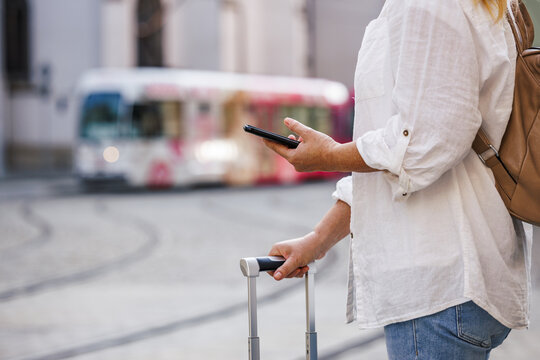 Woman tourist buying online ticket to tram with mobile app on her smart phone. Travel by public transportation in city