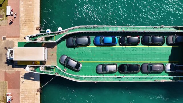 Ferry transporting vehicles across water at dock with vehicles lined up on deck