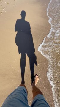 The shadow of a man walking along a sandy beach towards the sea. Baltic Sea, Poland