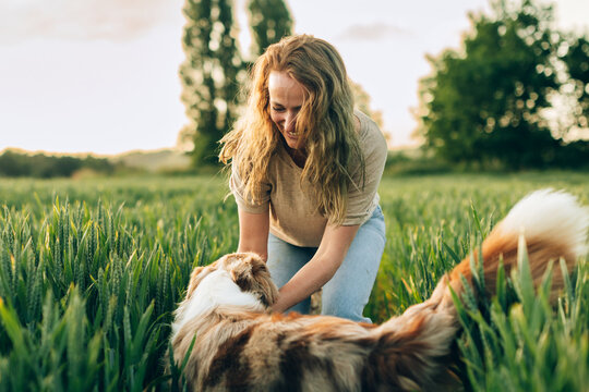 Woman bonding with dog in rural field at sunset