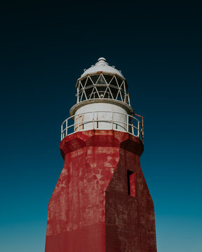 Vibrant red lighthouse tower against a clear blue sky in Newfoundland