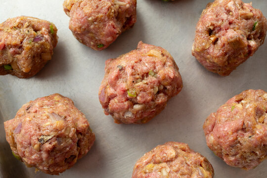 A top down view of a tray of raw bison meatballs.