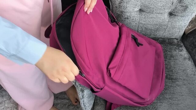Young woman putting books into backpack before class, studying, education and academic preparation concept.