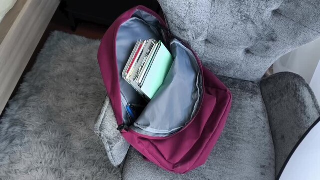 Backpack with books and school supplies on chair, preparing for school or university, student life and education concept.