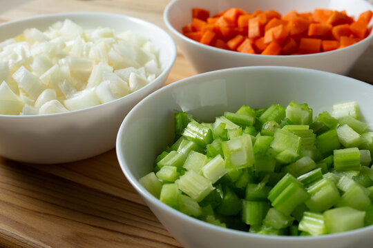 A view of some bowls of raw chopped mirepoix ingredients.