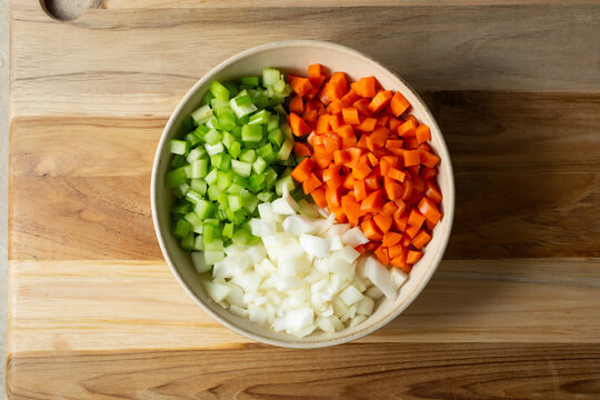 A top down view of a bowl of raw chopped mirepoix ingredients.