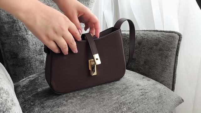 Woman emptying handbag onto chair while searching for personal belongings, everyday routine, handbag organization and lifestyle concept.