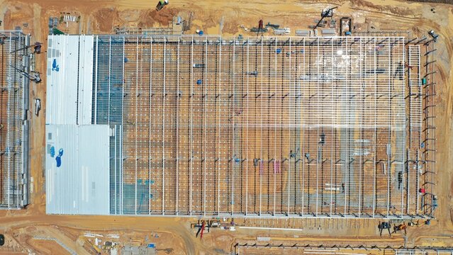 Industrial Construction Site: An aerial view captures a large-scale industrial construction project, showcasing the framework of a new building amidst ongoing development and infrastructure work.