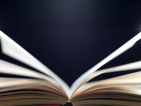 Pages of book falling open on black background