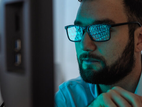 Programmer with eyeglasses hacking computer with virus